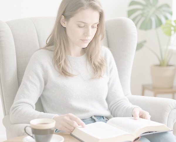Woman reading a devotional book with a cup of coffee